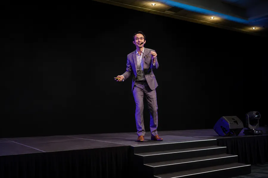 Kenneth Kwan presenting on a darkened main stage